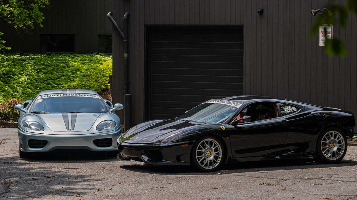 Two Ferrari 360 sports cars parked in front of a dark building.